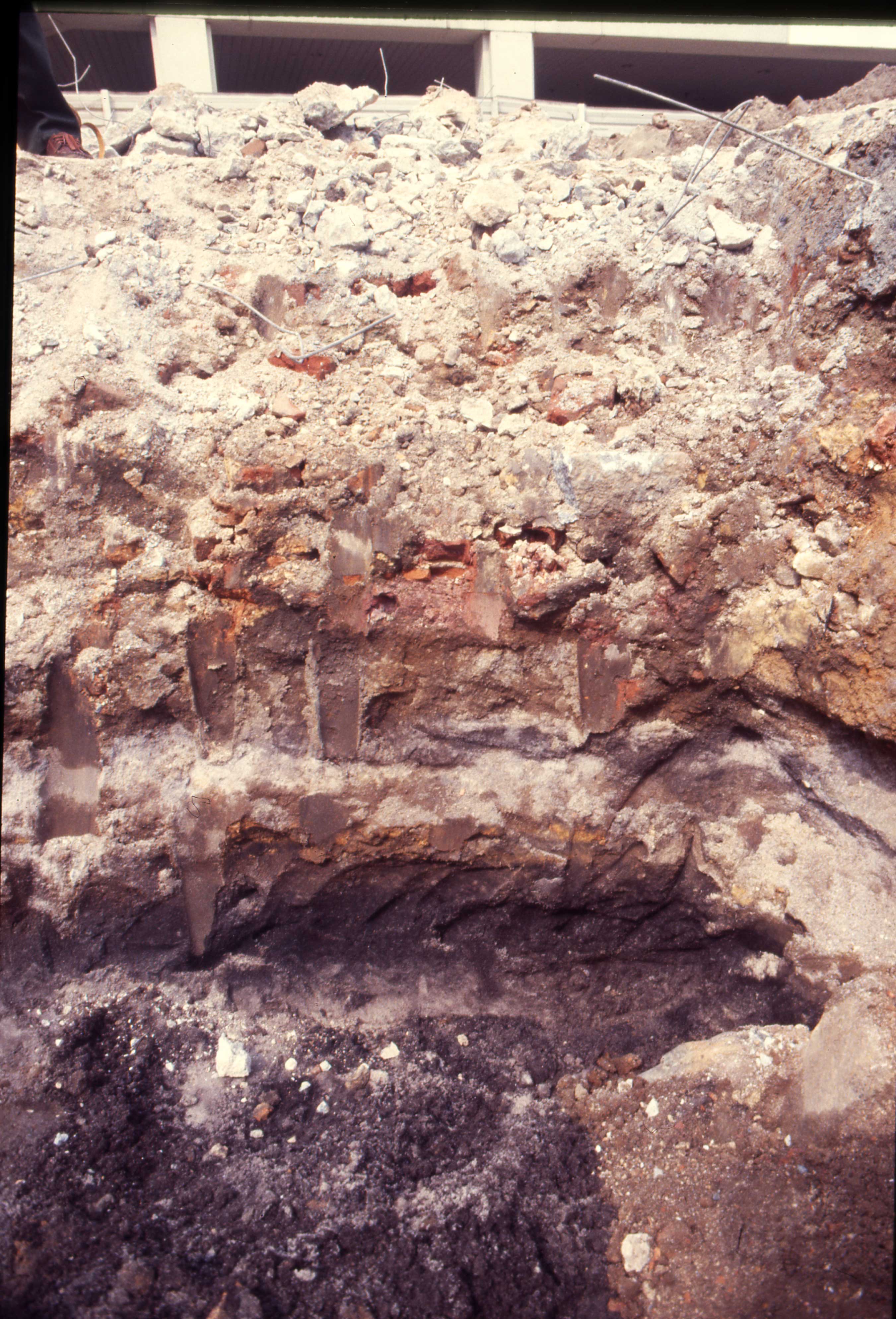 July 18 2000 profile of concrete, red soil, and black sand in backhoe trench.