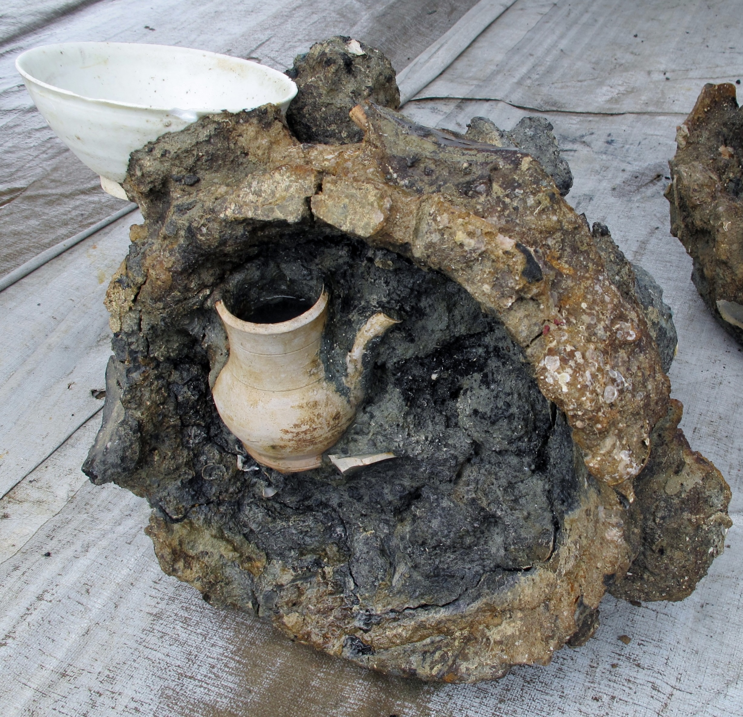 A ewer in a concretion of cast iron cauldrons.