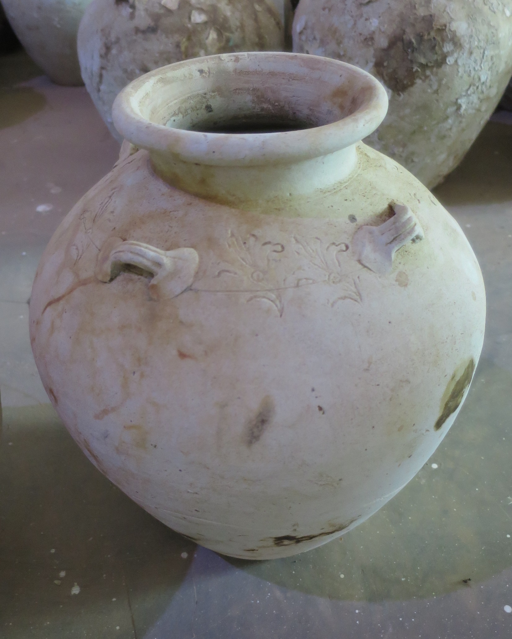 Jar with floral decoration on the shoulder, four lug-handles, a short straight neck and a folded mouth-rim. Flat base. Diameter 20-31 cm, height 27-40 cm.
