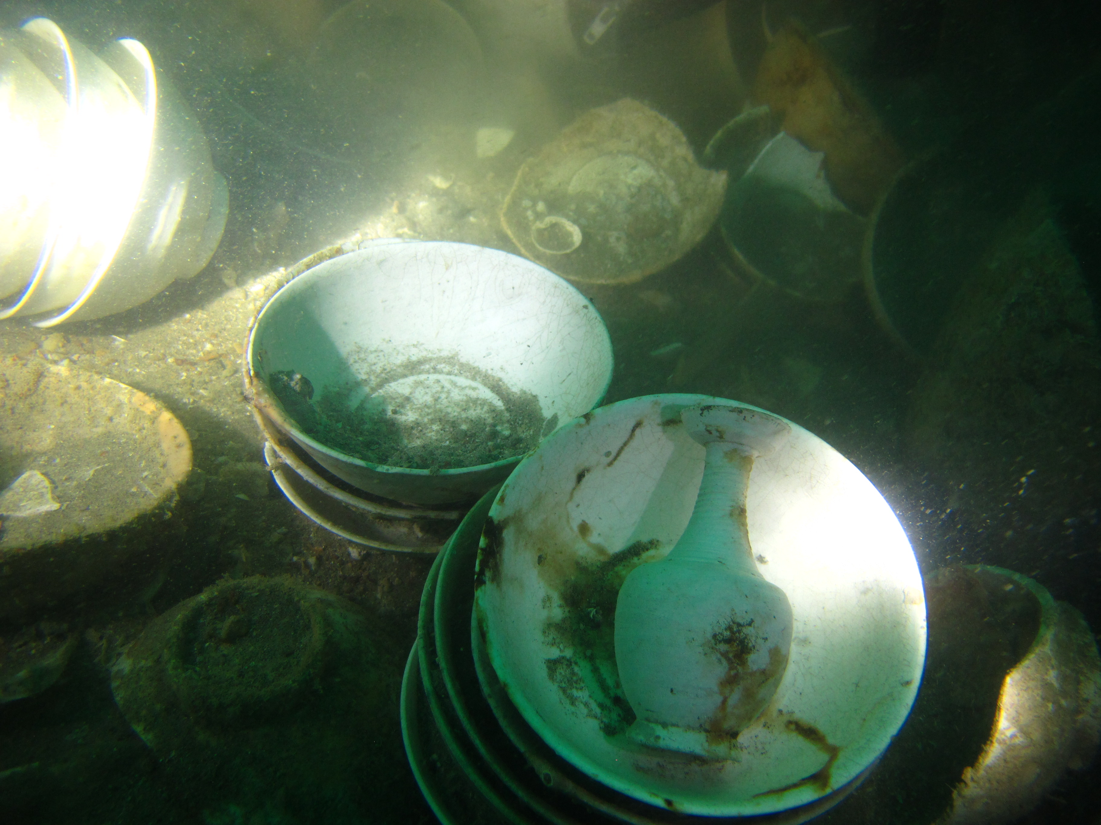 Stacks of bowls and a vase recovered from beneath the sediment.