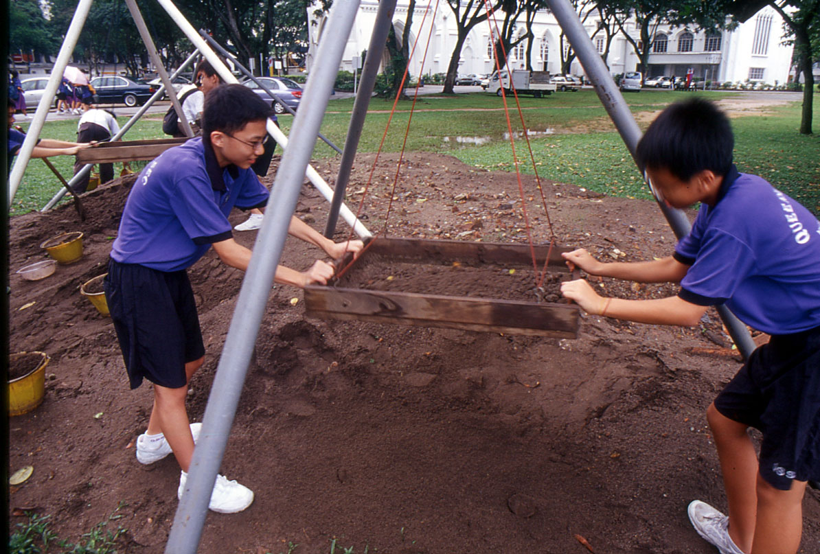 Figure 12: Two students from Queensway Secondary School sifting the excavated soil from the STA site