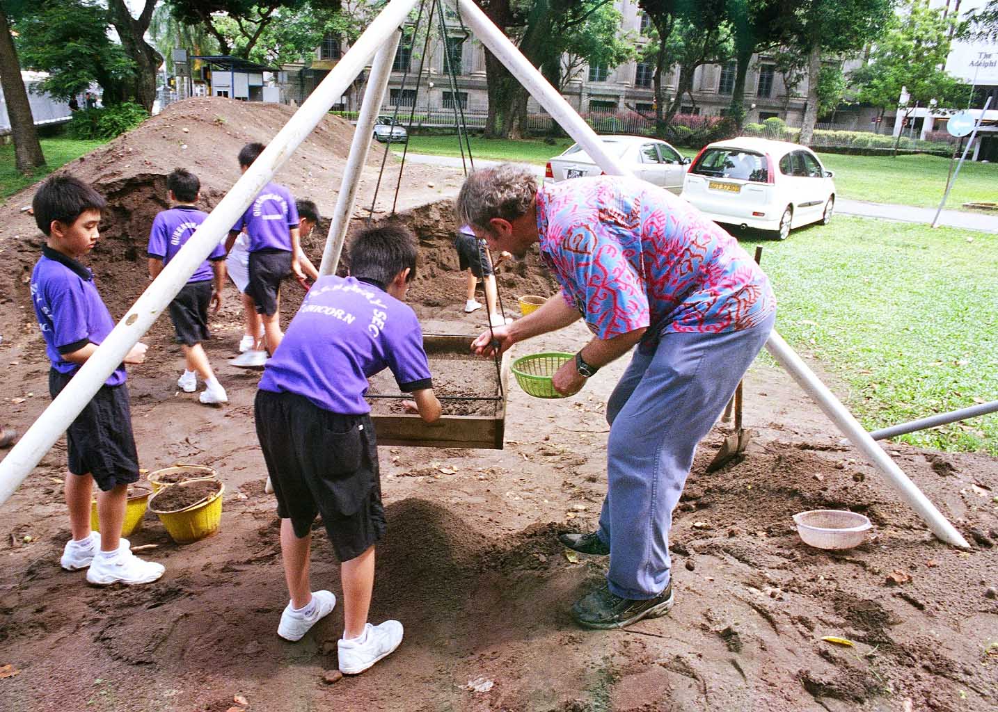Figure 13: One of the authors and Co-Investigator John Miksic sifting soil with one of the students from Queensway Secondary