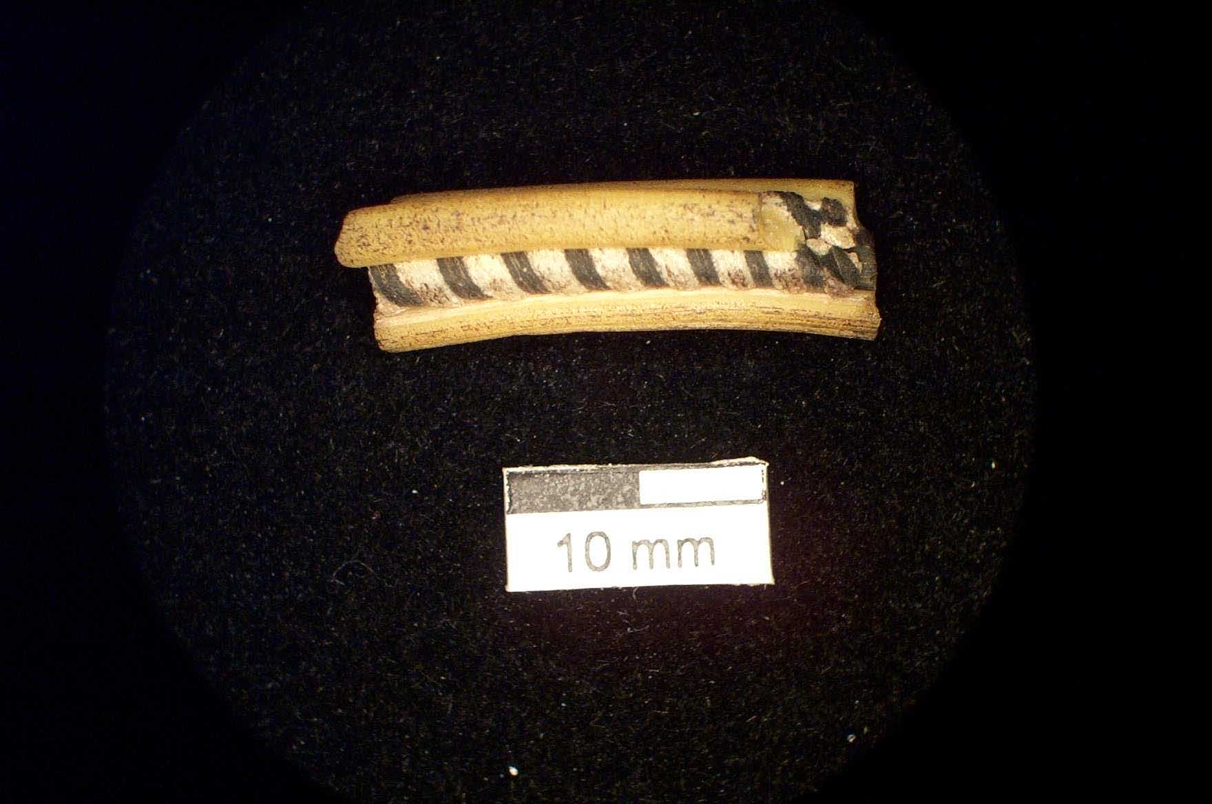Figure 15: Indian bangle which possesses a yellow body with red inlaid band within which are white globular insets of white opaque glass.